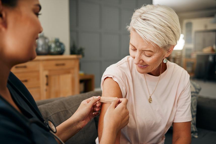 Home healthcare worker putting bandaid on senior woman